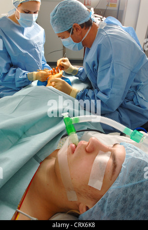 A surgeon and a nurse operate on a female patient's hand. Stock Photo