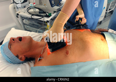 Doctors using a defibrillator to resuscitate a male heart attack victim. Stock Photo