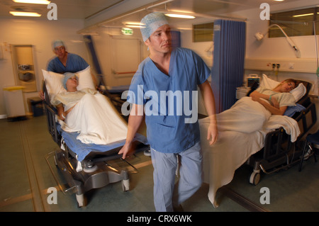 Two hospital porters wheeling patient on trolley bed to operating ...