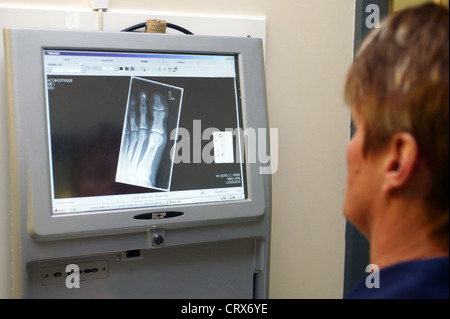 A female nurse looks at a digital x-ray on a computer. Stock Photo