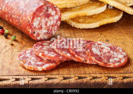 Salami on an old wooden board with toast. This is the ordinary, vacuum packed, supermarket salami. Stock Photo