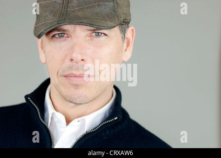 Close-up of a confident man in a newsboy hat looking at camera. Stock Photo