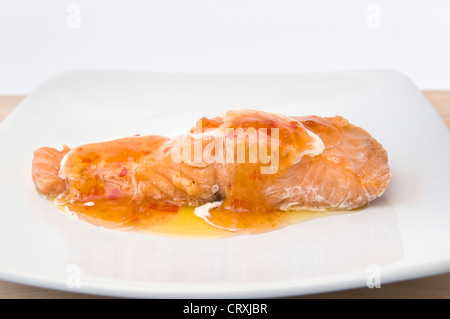 Cooked salmon with melted butter, creme fraiche and sweet chilli sauce on white plate Stock Photo