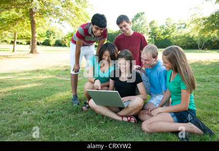 Divers group of teenagers looking at a computer outside Stock Photo