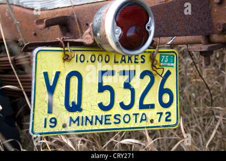 License plate from 1972 hanging on a dilapidated old truck on a farmer's field. Ottertail Minnesota MN USA Stock Photo