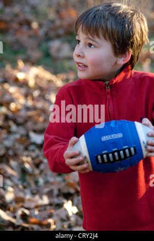 Boy age 5 playing touch football in backyard. Champlin Minnesota MN USA Stock Photo