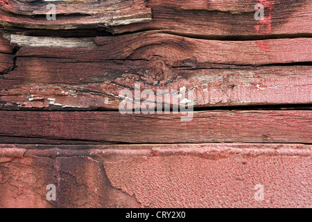 Stacked wooden beams with faint, flaking red paint at an industrial facility. Stock Photo