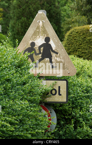 The 'school children crossing' sign is a British design classic. This pleasing faded and weathered example is at Milton Abbas, in Dorset. England, UK. Stock Photo