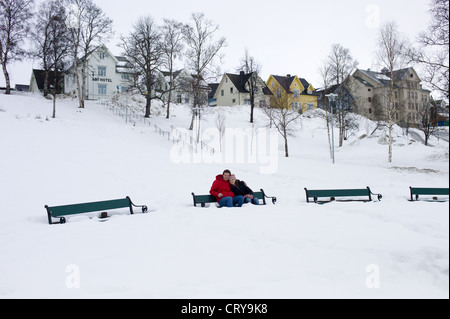 Young couple sitting on park bench in deep snow in Tromso, Norway Stock Photo