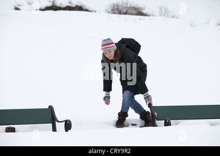 Young woman avoiding deep snow to reach park bench in snowy Tromso, Norway Stock Photo