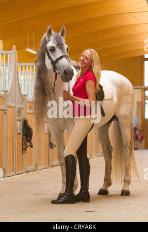 Pure Spanish Horse Andalusian Smiling woman with the stallion Napoleon standing in a stable Stock Photo