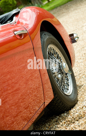 The rear wing and wheel of classic red vintage sports car with spoked wheel on gravel drive Stock Photo