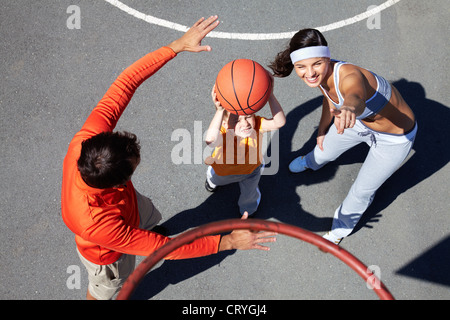 Active parents teaching their son how to play basketball Stock Photo