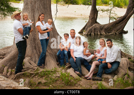 Portrait of a large family of three generations next to an old cypress tree near the Frio River in Concan Stock Photo
