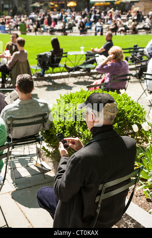 Mature man using mobile device while relaxing in park, NYC Stock Photo