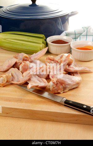 Raw Chicken wings being prepared for frying, on a wooded cutting board with celery and spices Stock Photo