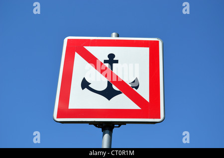 Warning sign prohibiting ships mooring riverside on background of blue sky. Anchor crossed red line. Stock Photo