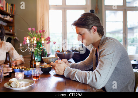Man using cell phone at dinner table Stock Photo