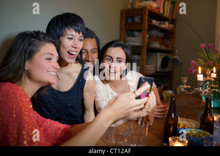 Friends using cell phone at dinner table Stock Photo