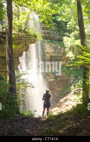 Woman stands in front of large waterfall Stock Photo