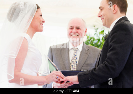 Bride putting ring on grooms finger Stock Photo