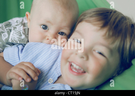 Baby boy and brother playing on couch Stock Photo