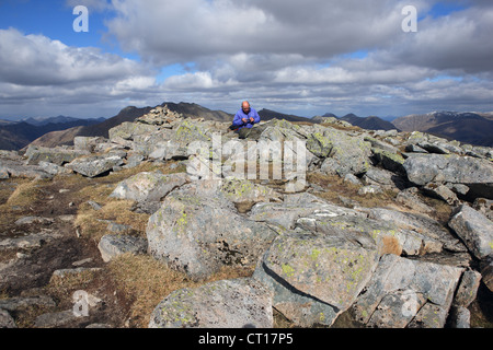 Man looking at the picture he has just taken on his camera at the summit of Sgor na h-Ulaidh (994m) near Glencoe in Scotland Stock Photo