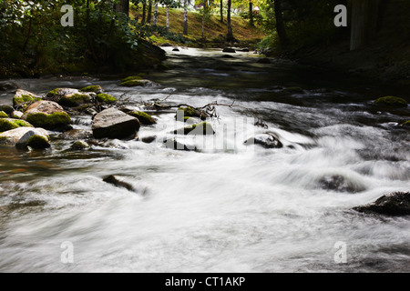 Blurred view of river rushing over rocks Stock Photo