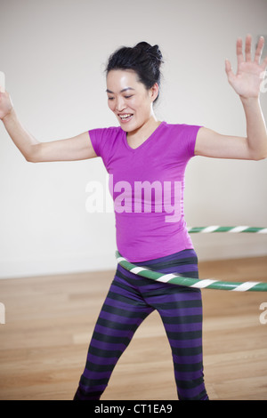 Woman using a hula hoop to exercise her waist muscles and midriff ...