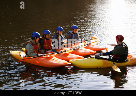 Teacher talking to students in kayaks Stock Photo