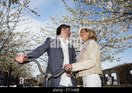Couple standing with bicycle in park Stock Photo