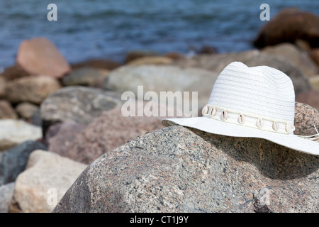 An white straw hat lies on a rock on the beach Stock Photo - Alamy