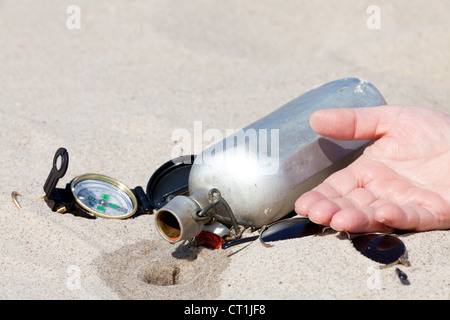 Human hand lies next to an empty canteen in the desert Stock Photo