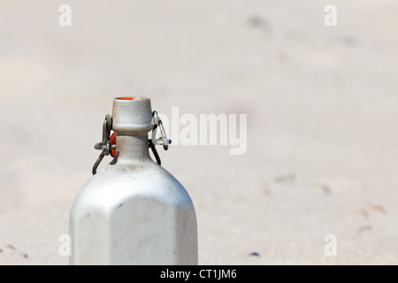 An empty canteen is in the desert sand Stock Photo