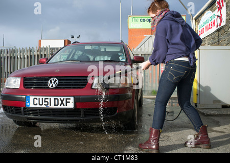 A 14 year old teenage girl earning pocket money by washing her family's VW Volkswagen passat estate car, UK Stock Photo