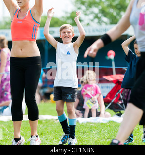 A boy exercising keeping fit at an outdoor zumba class UK Stock Photo