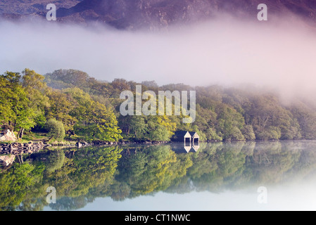 Boathouse on tree lined north western shore of a misty Llyn Dinas Lake in the Nantgwynant Valley Snowdonia North Wales Stock Photo