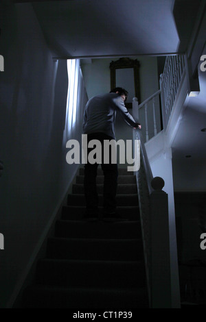 Back view of a young male walking upstairs in the dark. Stock Photo