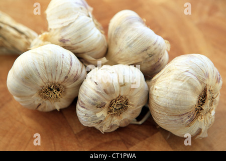 Garlic heads on a string on a wooden chopping board Stock Photo