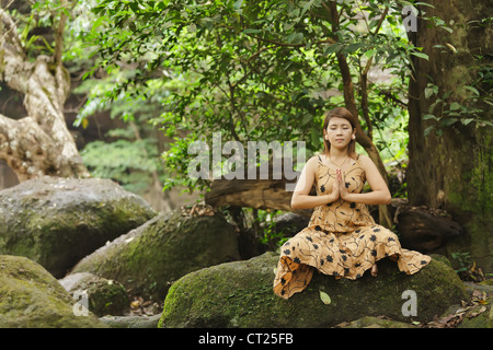 young asian woman meditating in wild forest, thailand Stock Photo