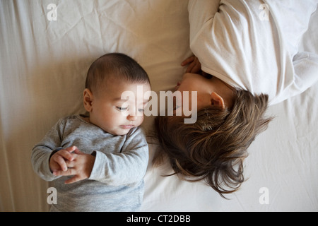A baby and a boy playing on a bed Stock Photo
