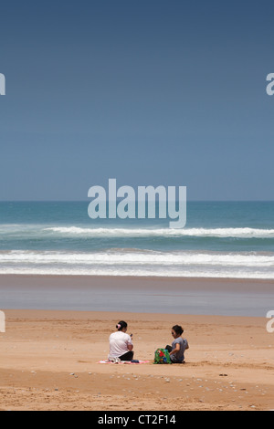 Two women sitting on a deserted beach near Agadir on the Atlantic coast, Morocco, Africa Stock Photo