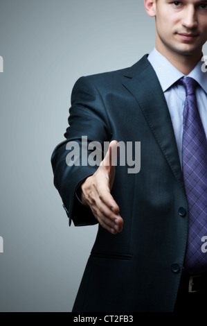 Business man extending hand to shake - focus on hand Stock Photo