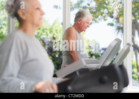 People and sports, elderly couple working out on treadmill in fitness gym Stock Photo