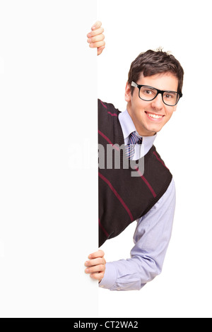Smiling handsome male posing behind a blank panel isolated on white background Stock Photo