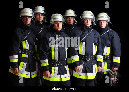 Firefighters in special fireproof suits, Nomex suit, helmet with visor, safety line. Professional fire eating. Stock Photo