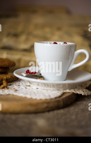 Crumbling oat cookies biscuits with hot coffee and whipped cream with cranberries on top. Shallow DOF Stock Photo