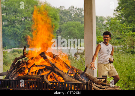 A body being cremated by the family and friend of deceased. rice is thrown on to the fire to help the body burn. Stock Photo