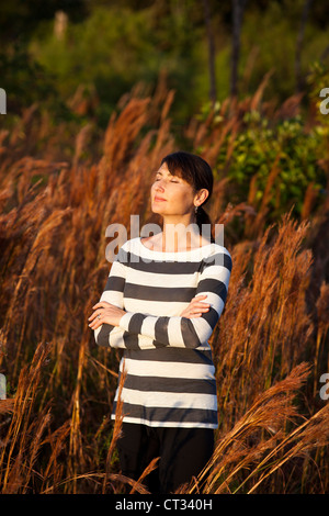 woman folding arms in field Stock Photo