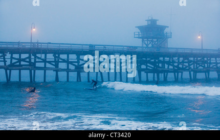 San Clemente pier with surfers on foggy day, California, USA Stock Photo